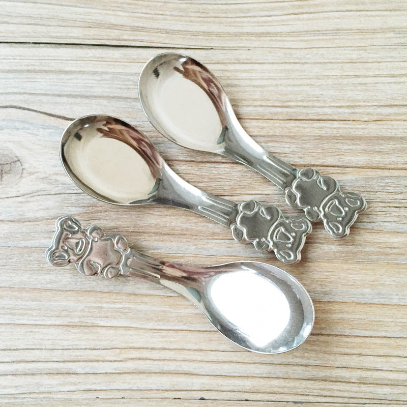 Three silver spoons with decorative handles on a wooden surface