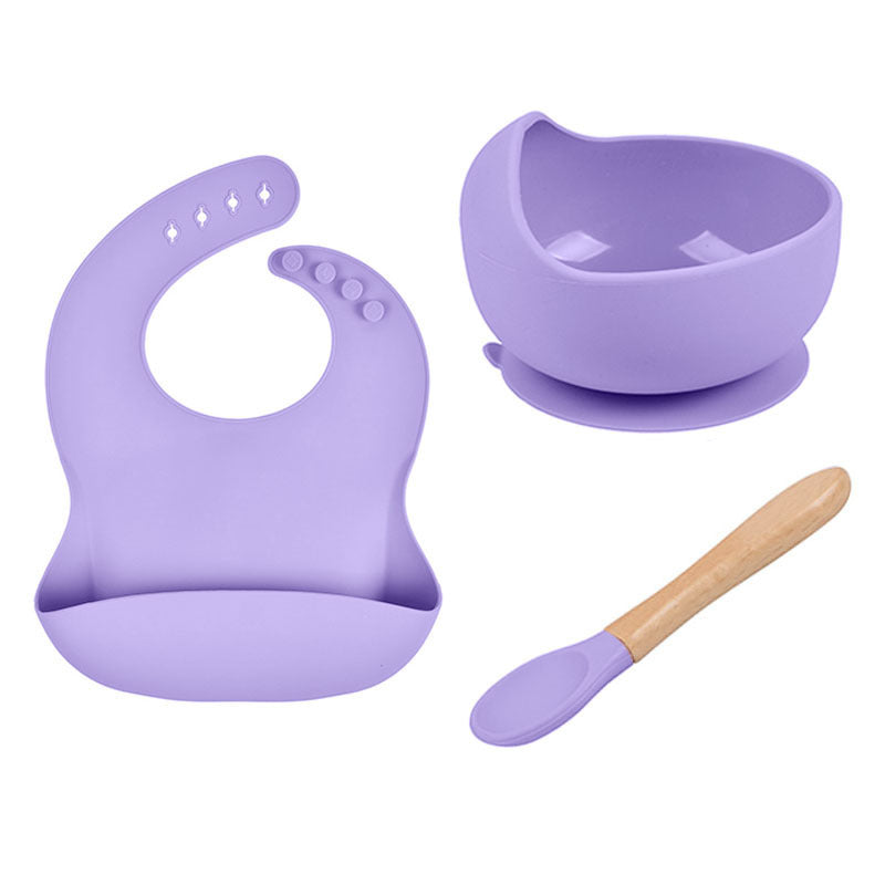 Purple baby bib, bowl, and spoon set on a white background