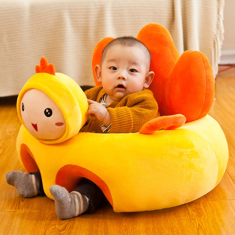 Child sitting in a yellow and orange plush toy chair on a wooden floor.