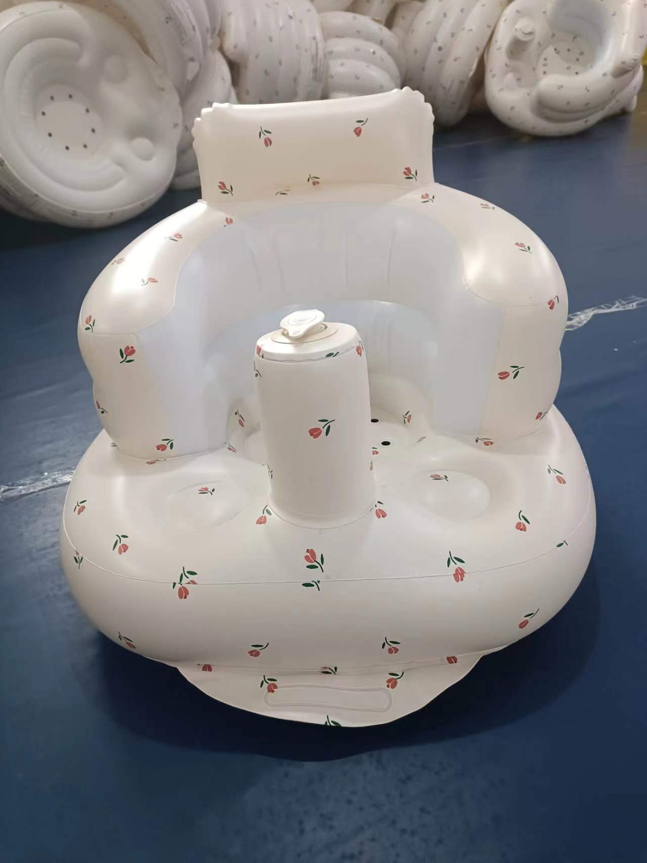 White inflatable baby seat with floral patterns on a blue surface