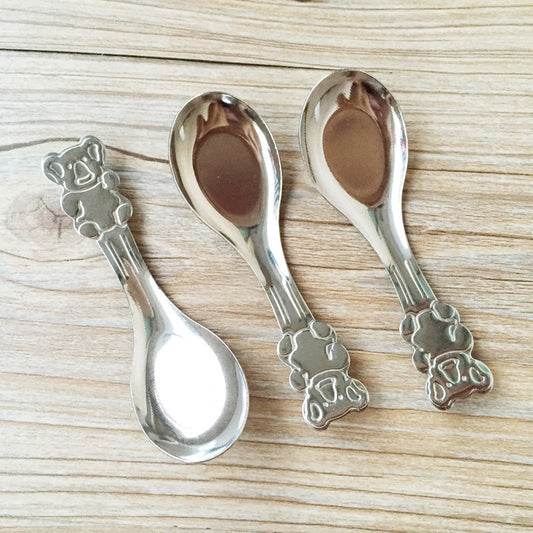 Three silver spoons with decorative handles on a wooden surface