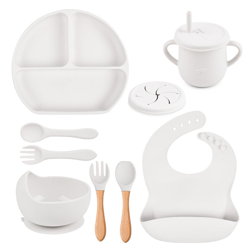 White baby dinner set with plate, cup, bowl, utensils, and bib on a white background