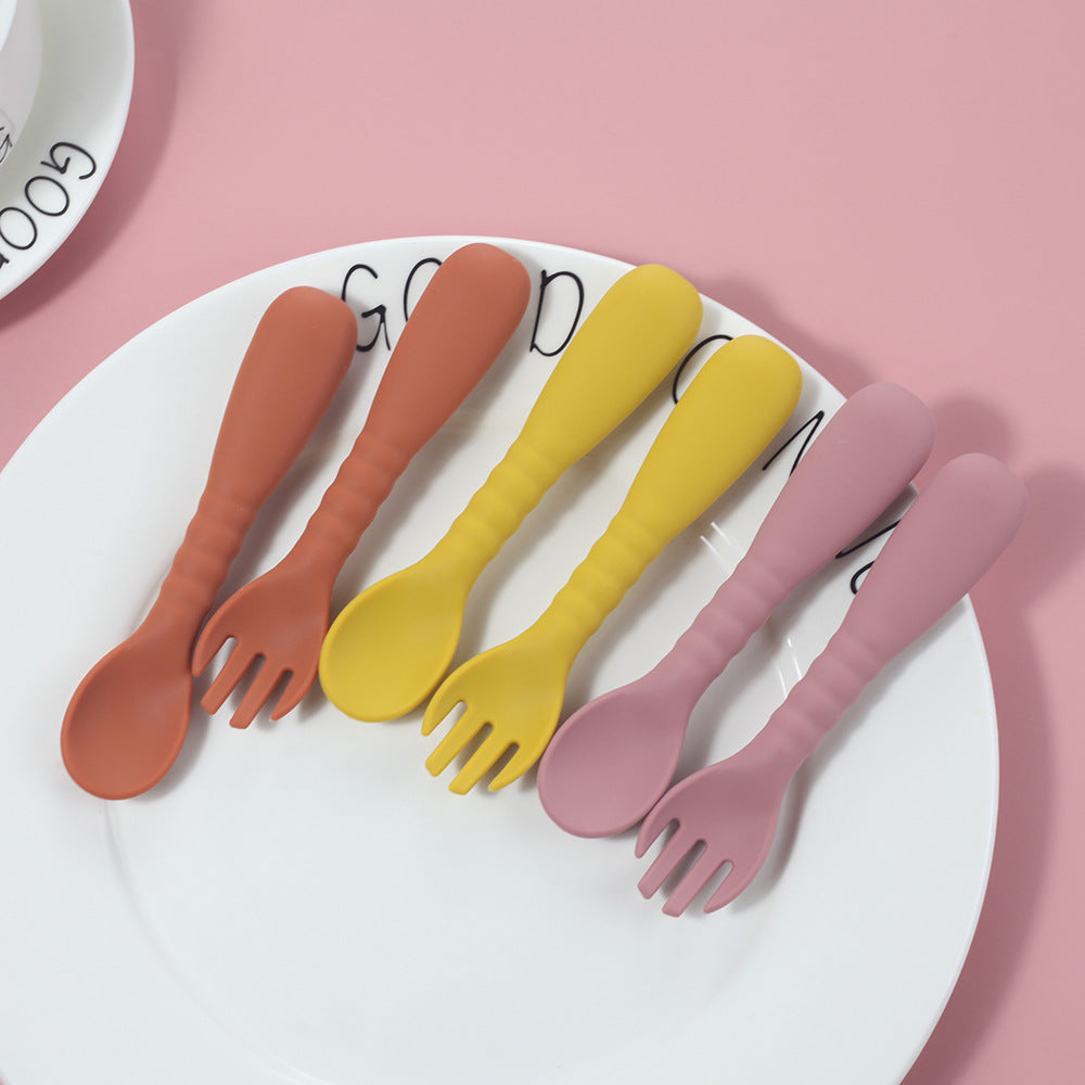 Set of colorful plastic forks on a white plate with a pink background