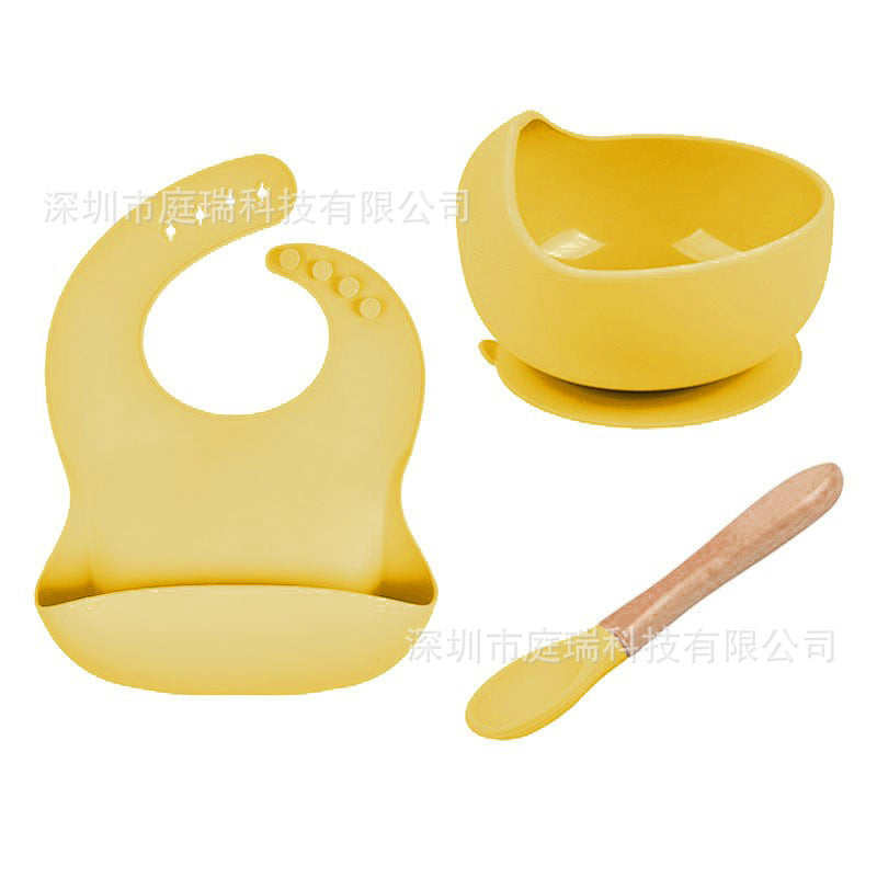 Yellow baby bib, bowl, and spoon set on a white background