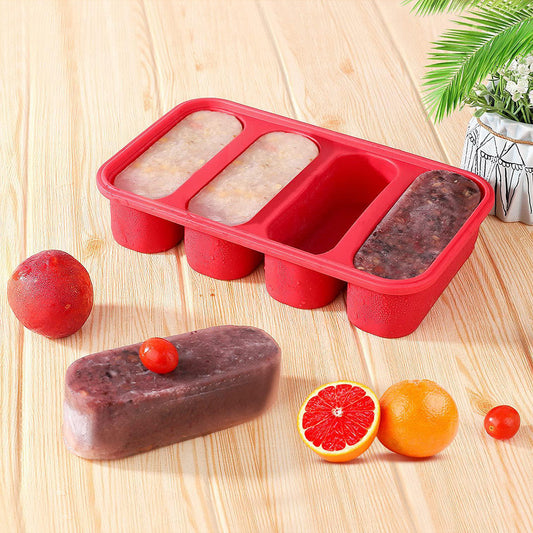 Red silicone ice cube tray with frozen fruit puree on a wooden surface