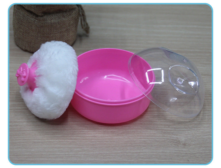 Pink container with a white scrubber and clear lid on a wooden surface