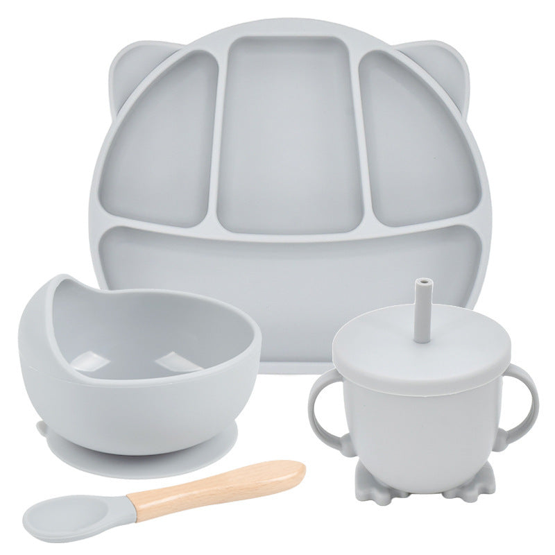 Set of gray silicone baby feeding utensils including a plate, bowl, cup with straw, and spoon on a white background.