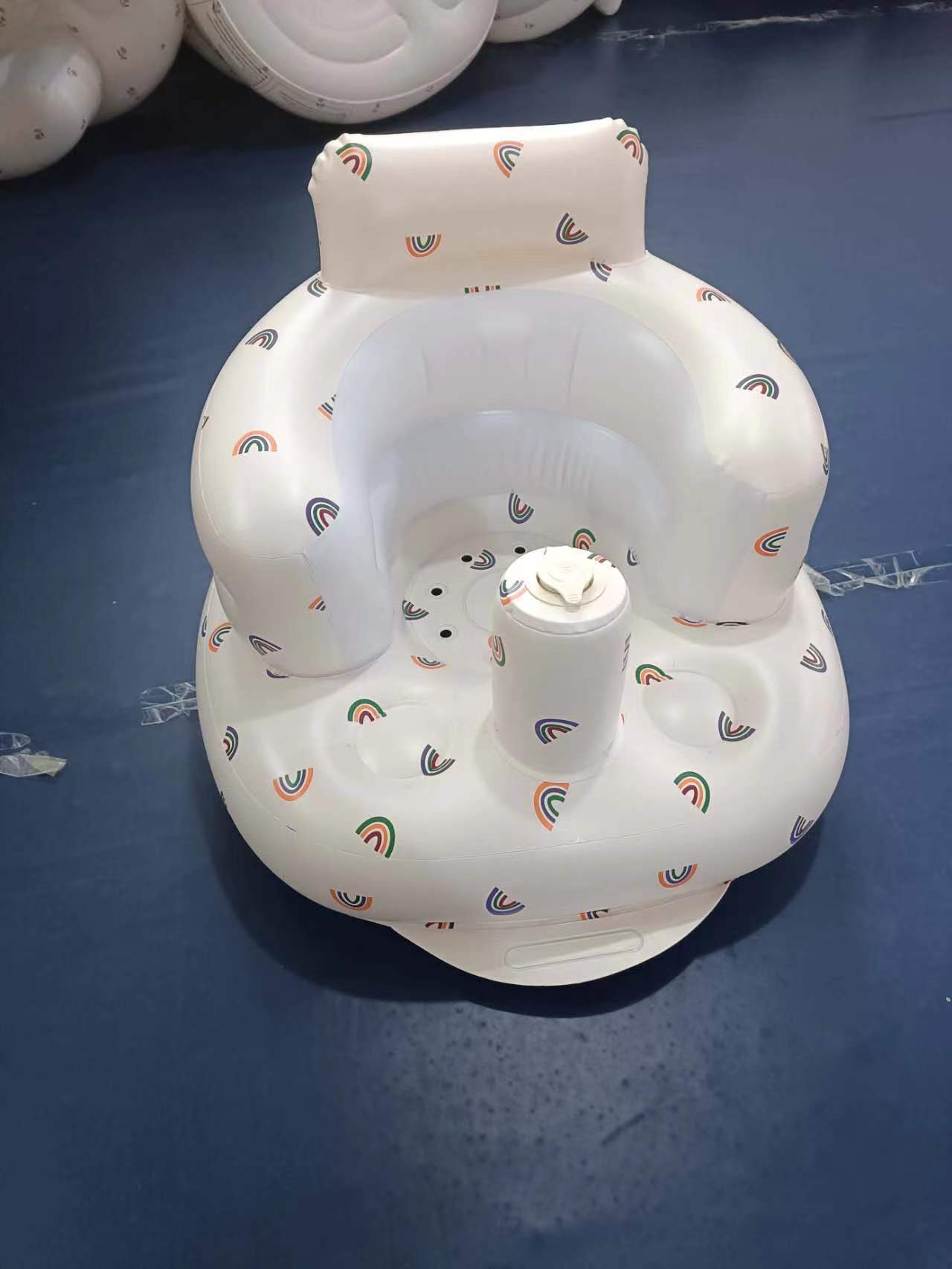 Inflatable baby seat with rainbow pattern on a blue surface