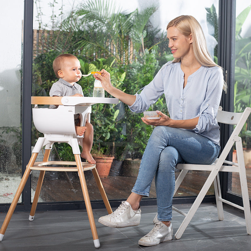 Woman feeding a baby in a high chair outdoors