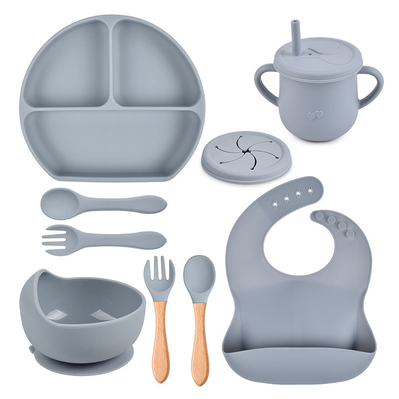Silicone dining set including plate, cup, bowl, utensils, and bib on a white background