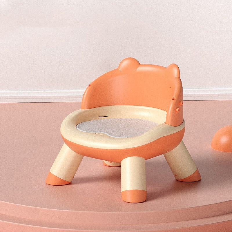 Children's potty chair with a bear design on a pink floor.